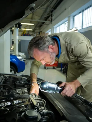 Mecánico examinar un coche con la lámpara
